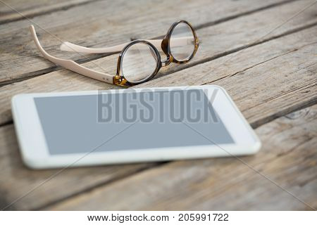Close up of eyeglasses and tablet computer on wooden table