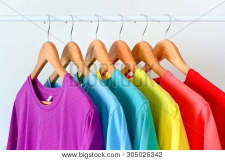 Close Up Collection Of Colorful Rainbow T-shirts Hanging On Wooden Clothes Hanger In Closet Or Cloth