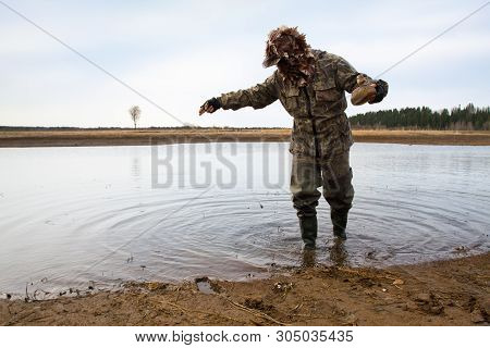 Duck Hunter Putting A Duck Decoy On The Shallow Water