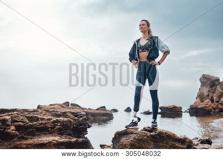 No Pain, No Gain. Confident Disabled Woman In Sportswear With Bionic Leg Standing On A Stone In Fron