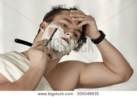 Young Handsome Caucasian Man With Electronic Watch On Wrist Shaves With Straight Razor (vintage Styl