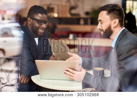 Two Businessmen Causacian And African American Having A Conversation In Cafe In Front Of Laptop, Thr