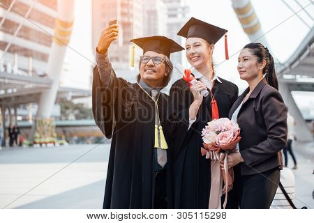 Capturing Happy Moments. Happy Father And Daughter In Graduation Gowns Making Selfie.