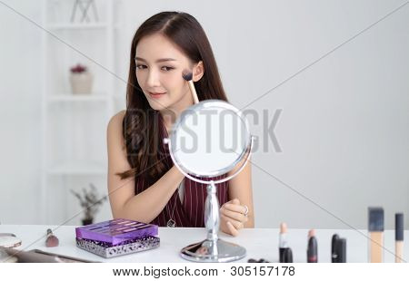 Portrait Of Beautiful Young Asian Woman Making Make-up Looking In The Mirror And Applying Cosmetic W