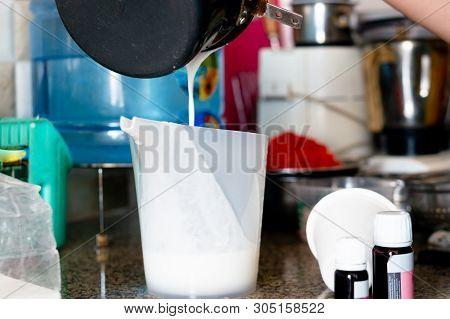 Molton Soap Base Being Poured From A Black Pan Into A Measuring Cup