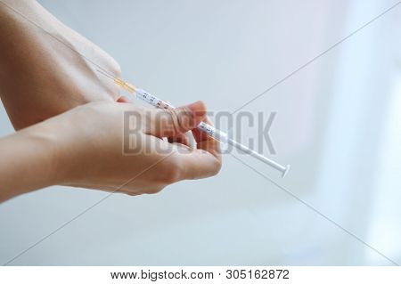 Doctor Or Nurse Hands In Medical Using Needle Syringe Drawing Blood Sample From Patient Arm In Hospi