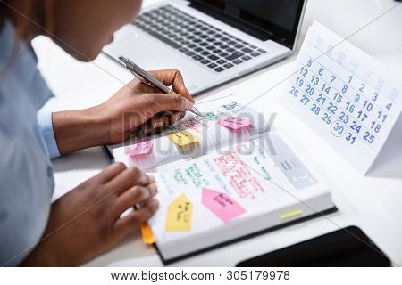 Businesswoman's Hand Checking Schedule In Diary