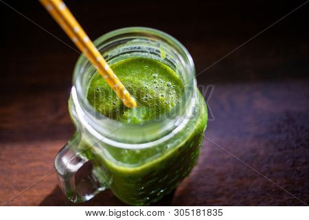 jar with green cold-pressed juice, wooden background. Healthy eating, detoxing, juicing body cleancing concept 