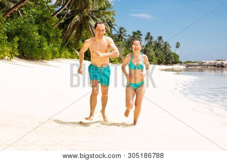 Happy Young Couple Running On Beach Enjoying The Vacations