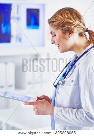 Young Woman Doctor Is Standing With Board With Clipboard Smilin