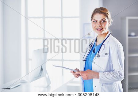 Young Woman Doctor Is Standing With Board With Clipboard Smilin
