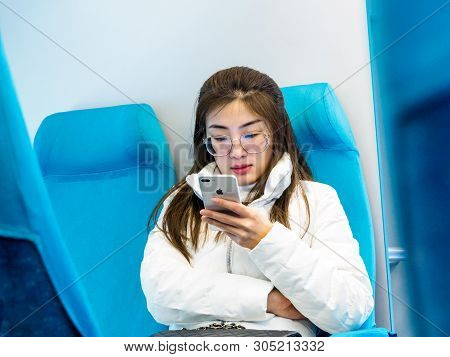 Shanghai, China 13 March 2019 - A Young Chinese Woman Uses An Apple Iphone On The Maglev Train Headi