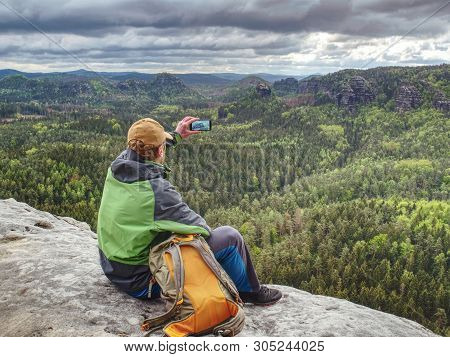 Man Tourist In Nature. Spring Free Day In Rocky Mountains. Hiker With Sporty Backpack Stand On Rocky