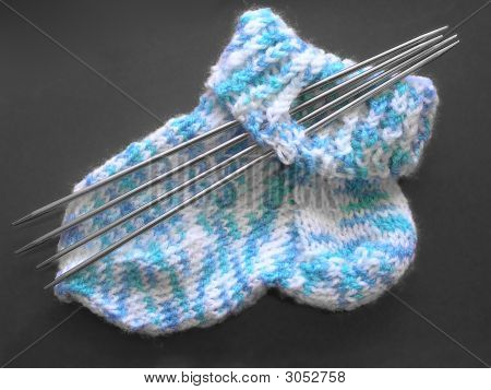 Gestrickte Socke und Nadeln auf grau