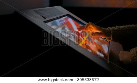 Woman Using Interactive Touchscreen Display In Modern Historical Museum. Evening Time, Lowlight. Edu