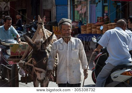 Kashgar, Xinjiang, China - August 14, 2012: Uyghur Man With A Donkey At A Street Market In The City 