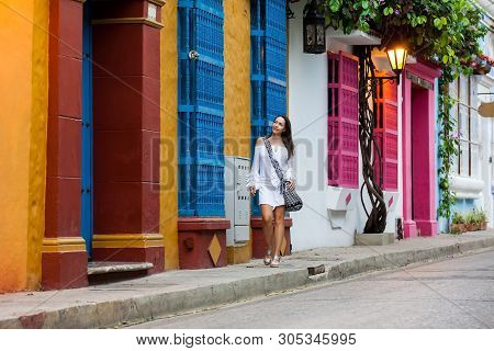 Beautiful Woman On White Dress Walking Alone At The Colorful Streets Of The Colonial Walled City Of