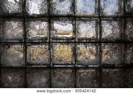 Building Of An Abandoned And Destroyed Farm Is Seen Through A Partially Broken, Dirty Window Of Glas