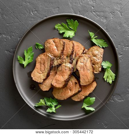 Grilled Beef Liver On Plate Over Black Stone Background. Cooked Liver(offal) From Beef Meat. Top Vie
