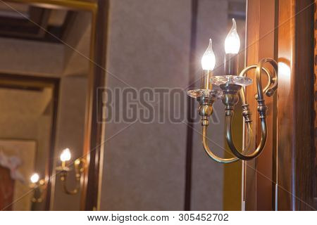 Retro Copper Candlestick Hanging On The Wall. Vintage Golden Candlestick With Light Bulbs. Gold Wall