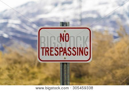Close Up Of White Sign Board With The Words No Trespasing Painted In Red Color