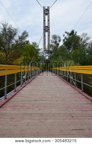 View Of The Bridge With Yellow Railings And Cables Across The River On Mount Kizilovka In The Foothi