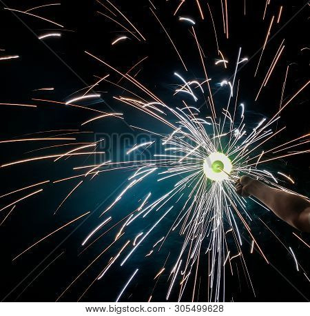 Hand Charki, A Hand Firework Emitting Circular Sparks In Black Background