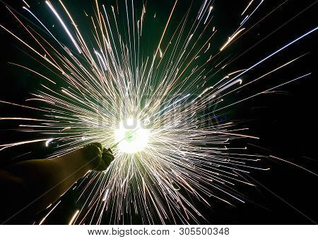 Hand Charki, A Hand Firework Emitting Circular Sparks In Black Background
