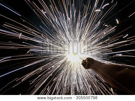 Hand Charki, A Hand Firework Emitting Circular Sparks In Black Background