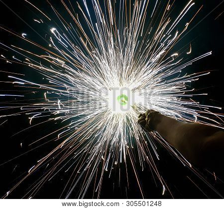 Hand Charki, A Hand Firework Emitting Circular Sparks In Black Background