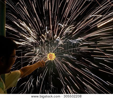A Man Holding Hand Charki, A Hand Firework Emitting Circular Sparks In Black Background