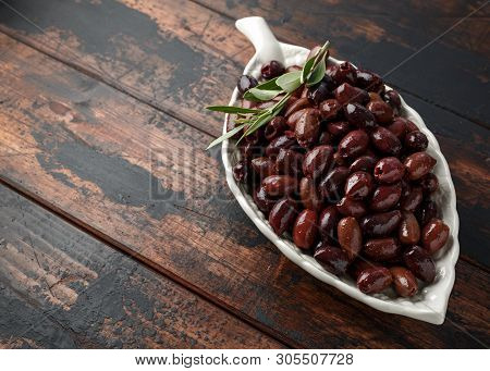 Pitted Kalamata Olives In Bowl On Rustic Wooden Background
