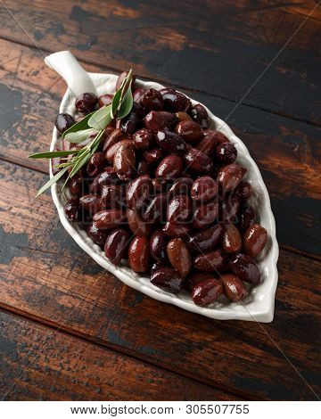 Pitted Kalamata Olives In Bowl On Rustic Wooden Background