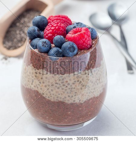 Layered Chocolate And Peanut Butter Chia Seed Pudding In A Glass, Garnished With Raspberry And Blueb