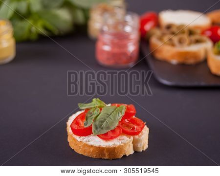 Italian Bruschetta With Cream Cheese, Tomato Cherry And Bazil And Bruschetta In Assortment On The Pl