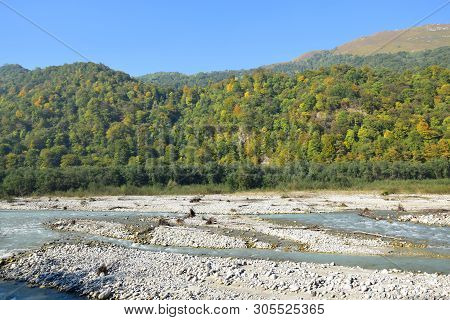 Panorama Of The Fast Mountain River With Blue Water With Stones And Mountains With Green Trees In Th