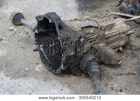 An Old And Dirty Gearbox Lies On The Ground With Axles
