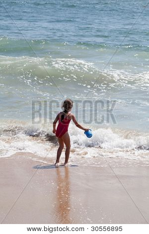 Bambina giocando con un secchio sulla spiaggia