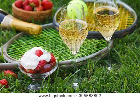 Enjoing In Wimbledon Tennis Championship With Champagne And Strawberries With Cream. Wimbledon Symbo