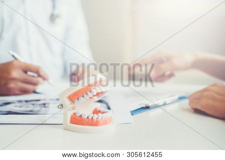 Dentist Talking To Male Patient And Presenting Results On Dental X-ray Film About The Problem Of The