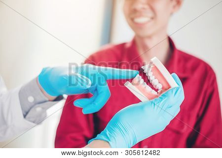 Dentist Talking To Male Patient And Presenting Results On Dental X-ray Film About The Problem Of The