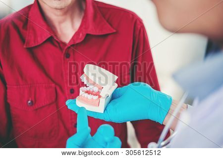 Dentist Talking To Male Patient And Presenting Results On Dental X-ray Film About The Problem Of The