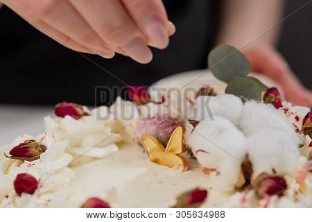 The Condater Sprinkles The Cake With Grated Almonds And Coconut. Close-up Of A Hand And Pouring Crum