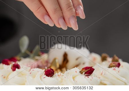 The Condater Sprinkles The Cake With Grated Almonds And Coconut. Close-up Of A Hand And Pouring Crum
