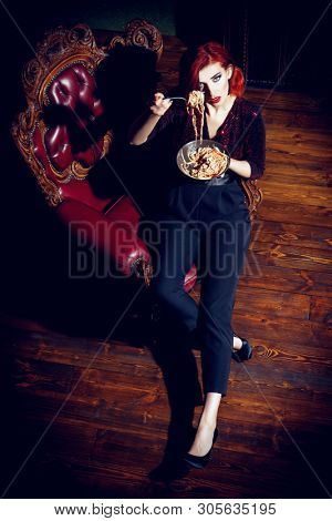 A full length portrait of a beautiful woman posing in the vintage interior and having a meal. Beauty, fashion, interior.