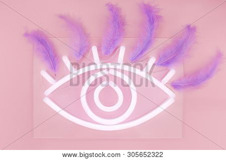Glowing Neon White Eye Sign With Eyelashes On A Pink Background. Flat Lay, Top View. Trends 2019.