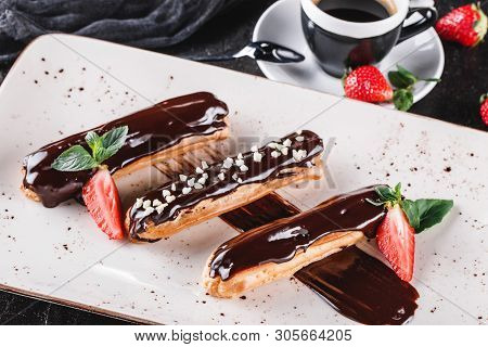 Homemade Cake Eclairs Or Profiteroles With Custard, Chocolate And Strawberries On Dark Background Se