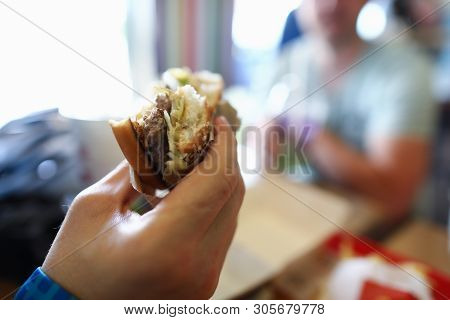 Male Hand Hold Teasty Burger In Hand Aganist Cafe Background