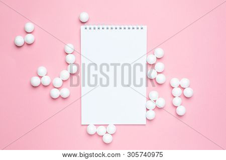 Business Notebook And White Plastic Balls On Pink Background. Abstract Concent.