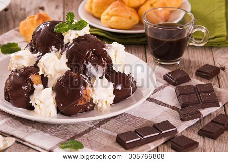 Chocolate Profiteroles With Whipped Cream On White Dish.